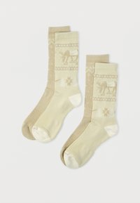 Megzti smėlio spalvos ir šviesiai geltoni kojinai su elastiniu raštu, kuriame pavaizduoti elniai ir snaigės. Minkšta tekstūra, ribuota apyrankė ir sustiprintas pirštų galas.