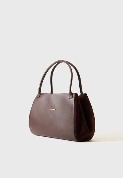 Sac à main en cuir marron avec deux poignées courbées et un petit accent doré horizontal sur le devant sur un fond uni.