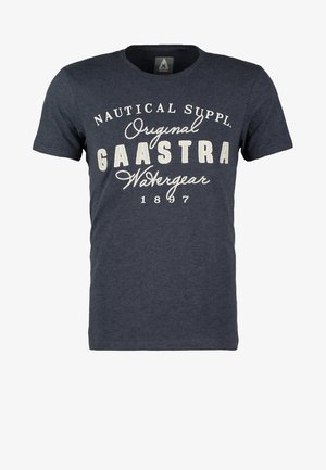 Man loopt en draagt een marineblauw grafisch t-shirt, grijze jeans met omslagen, zwart-grijze sneakers en draagt een grijze jas over zijn schouder.