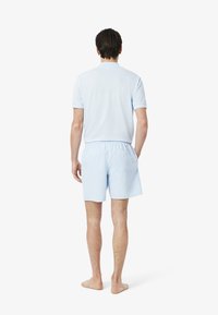 Lichtblauwe polo met bijpassende shorts, gemaakt van zachte stof, met korte mouwen en een elastische tailleband.