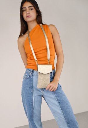 Bolso cruzado dorado con sección inferior texturizada y tapa superior lisa. Combínalo con una blusa sin mangas naranja y pantalones de mezclilla de cintura alta.