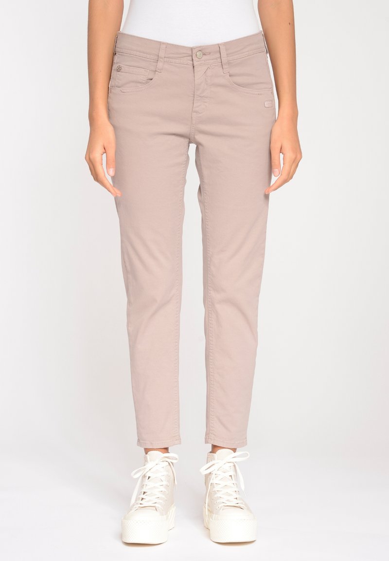 Beiga slim-fit byxor tillverkade av en bomullsblandning, med framfickor och knappstängning. Tillsammans med vita högstående sneakers.