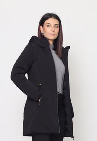 Giacca nera con cappuccio, zip frontale, due tasche laterali e fodera interna trapuntata in materiale morbido e liscio. Presenta dettagli in oro.