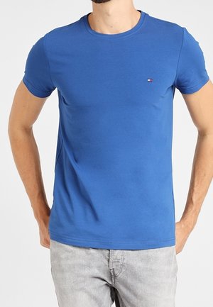 Camiseta de algodón azul con cuello redondo, mangas cortas y un pequeño logo en el pecho. Textura suave y diseño de ajuste regular.
