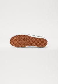 Semelle de chaussure en caoutchouc avec un motif texturé en nid d'abeille. La couleur dominante est l'orange avec des bords blancs, et un accent de logo en rouge.