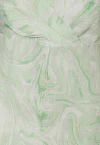 Vestido verde claro com um padrão de mármore em tons de branco e verde. O tecido tem uma textura suave com um brilho sutil.