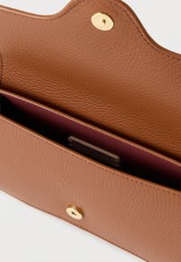 Portafoglio in pelle marrone con superficie testurizzata, dotato di chiusura a scatto dorata e interno in un profondo color bordeaux. Tasca interna visibile.