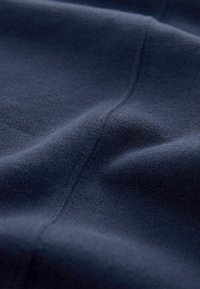 Tissu bleu marine avec un motif tricoté texturé, présentant une surface douce et lisse ainsi que des plis subtils indiquant flexibilité et tombé.