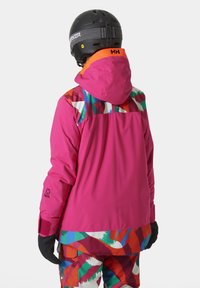 Roze sneeuwjack met kleurrijke geprinte accenten op de schouders, voorzien van een capuchon en verstelbare manchetten, gecombineerd met bijpassende geprinte broek.