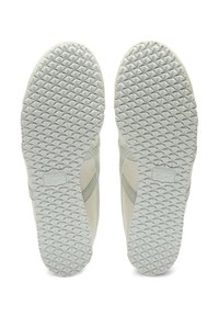Białe podeszwy trampek z teksturą w diamentowy wzór, z gładkim wykończeniem i wytłoczonym logo z boku.