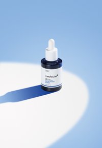 Niebieska szklana butelka z kroplomierzem, oznaczona jako "medicube Zero Pore One Day Serum", z białym kroplomierzem i czystym, minimalistycznym designem.