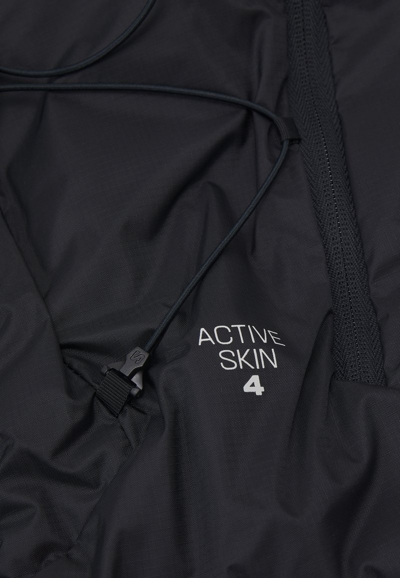 Veste de sport en tissu noir avec fermeture éclair à l'avant, cordon de serrage réglable et logo en relief "ACTIVE SKIN 4" sur la poitrine.