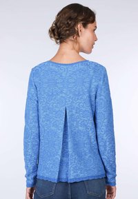 Blauer Langarmpullover mit strukturiertem Blumenmuster und rundem Ausschnitt, mit einer Rückenfalte und gewelltem Saum.