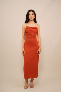 Ribbel, aansluitende midi-jurk in roestoranje met dunne bandjes en een geplooide buste. Gemaakt met gouden bandjeshakken en minimale sieraden.