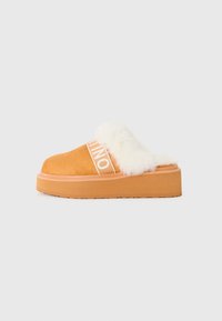 Brun plattform slip-on sko med hvit fôr og synlig merkevare-elastisk stropp på hvit bakgrunn.