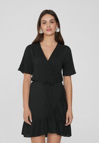Schwarzes Wickelkleid mit kurzen, schwingenden Ärmeln, V-Ausschnitt, tailliertem Gürtel und rüschendem Saum. Glatte Textur, leichtes Material.