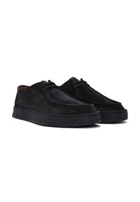 Zapatos de ante negros con un perfil bajo y punta redondeada. Presentan costuras en contraste y una suela de goma texturizada para mayor agarre. Diseño con cordones.