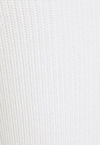 Tissu blanc tricoté avec une texture côtelée, présentant des lignes verticales et un aspect doux. Aucun matériel notable ni motifs présents.