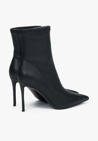 Zwarte leren enkellaarsjes met een puntige neus en hoge stilettohak. De gladde textuur en het strakke ontwerp versterken de moderne silhouet.