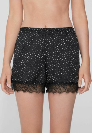 Shorts de nuit en satin noir avec des pois blancs, ornés d'une élégante bordure en dentelle noire au bas. Ceinture élastique pour plus de confort.