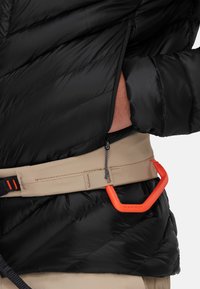 Zwarte pufferjack met een gestikt ontwerp, gecombineerd met een beige riem met een oranje plastic karabijnhaak en een ritsdetail.