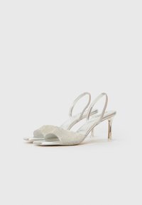 Sølv slingback hæle med en tekstureret overdel og rhinestone-detaljer, åben tå-design og en slank gennemsigtig hæl.