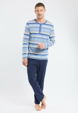 Haut de pyjama à manches longues rayé en bleu, crème et marine avec une patte de boutonnage à trois boutons, associé à un pantalon élastique uni marine à taille élastique.
