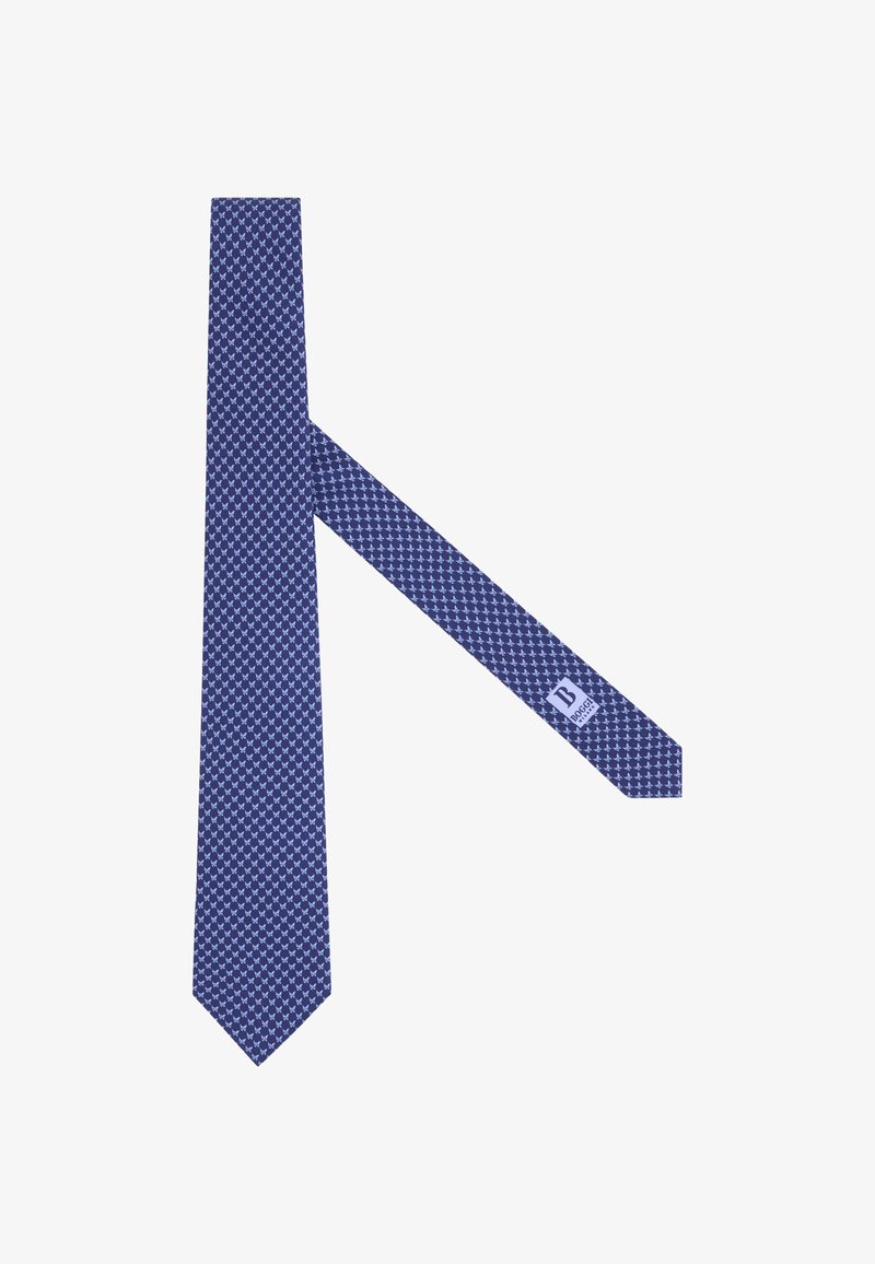 Cravate bleue avec un petit motif répétitif de formes abstraites bleu clair, affichant l'étiquette de marque sur l'extrémité étroite.