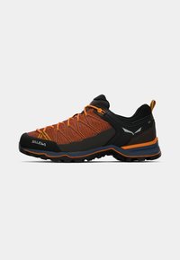 Sportschoen met een ademend oranje en zwart gaas bovenwerk, versterkte neus, contrasterende oranje veters en robuuste zwarte buitenzool voor grip.