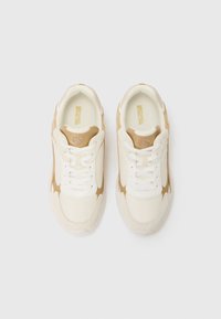 Sneakers bianchi e beige con una tomaia in rete e suede, forma tondeggiante, design con lacci e un piccolo logo sul lato e sulla linguetta.