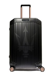 Schwarzer Hartschalen-Koffer mit vertikalen Rillen, kupferfarbenem Griff und Rollen. Verfügt über ein dezentes Logo auf der Vorderseite.