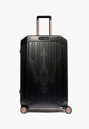Schwarzer Hartschalen-Koffer mit vertikalen Rillen, kupferfarbenem Griff und Rollen. Verfügt über ein dezentes Logo auf der Vorderseite.