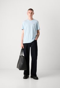 Tricou albastru deschis cu mânecă scurtă, blugi negri drepți și geantă din piele neagră. Oferind un aspect minimalist, casual, fără modele proeminente.