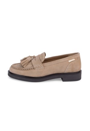 Beige suède loafer met zwarte zool, decoratieve kwastjes bovenop en gestikte details langs de voorkant.