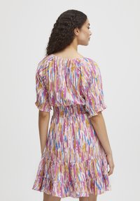 Rochie cu imprimeu floral, cu mâneci scurte tip bufant, talie elastică, modele multicolore pe un fundal roz și tiv ondulat.