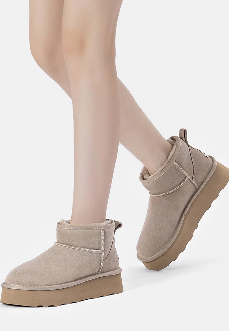 Beige Wildleder-Ankle Boots mit einer weichen, strukturierten Oberfläche, einer abgerundeten Zehe und einer dicken, beige Gummisohle. Das Design umfasst einen umgeschlagenen Schaft.