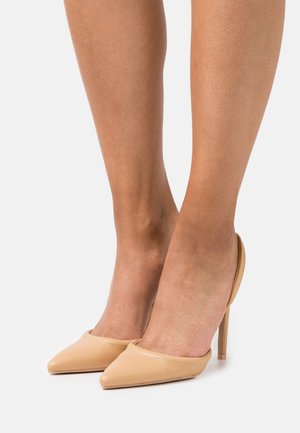 Sapatos de salto alto de bico fino em bege com parte traseira aberta, feitos de couro liso. Apresenta um silhueta elegante e detalhes em costura ao longo das bordas.
