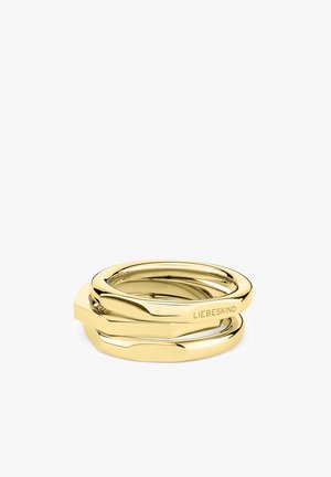 Gold-tone three interlocking rings with a polished finish. Features smooth surfaces and a subtle, engraved logo on one band.