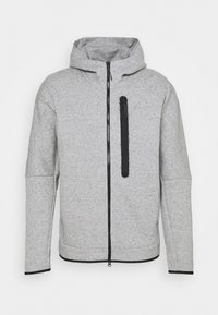 Šedá mikina na zip z texturované látky. Má přední kapsu na zip, kapuci a kontrastní černé detaily podél zipu a kapsy.