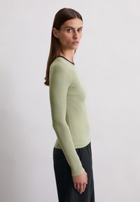 Ribbed knit long-sleeve top in light green with a contrasting navy round neckline, displayed in a side view against a neutral background.