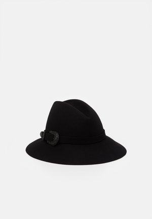 Czarny kapelusz fedora z szerokim rondem i ozdobną czarną klamrą na opasce, przedstawiony na jednolitym białym tle.