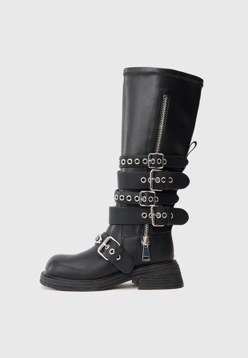 Bota de cuero negro hasta la rodilla con múltiples correas ajustables, herrajes plateados, cremallera lateral y suela texturada.