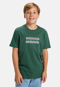 Zielona bawełniana koszulka z grafiką w kratkę oraz napisem "Quiksilver" w kolorze różowym i turkusowym. Krótkie rękawy, okrągły dekolt.