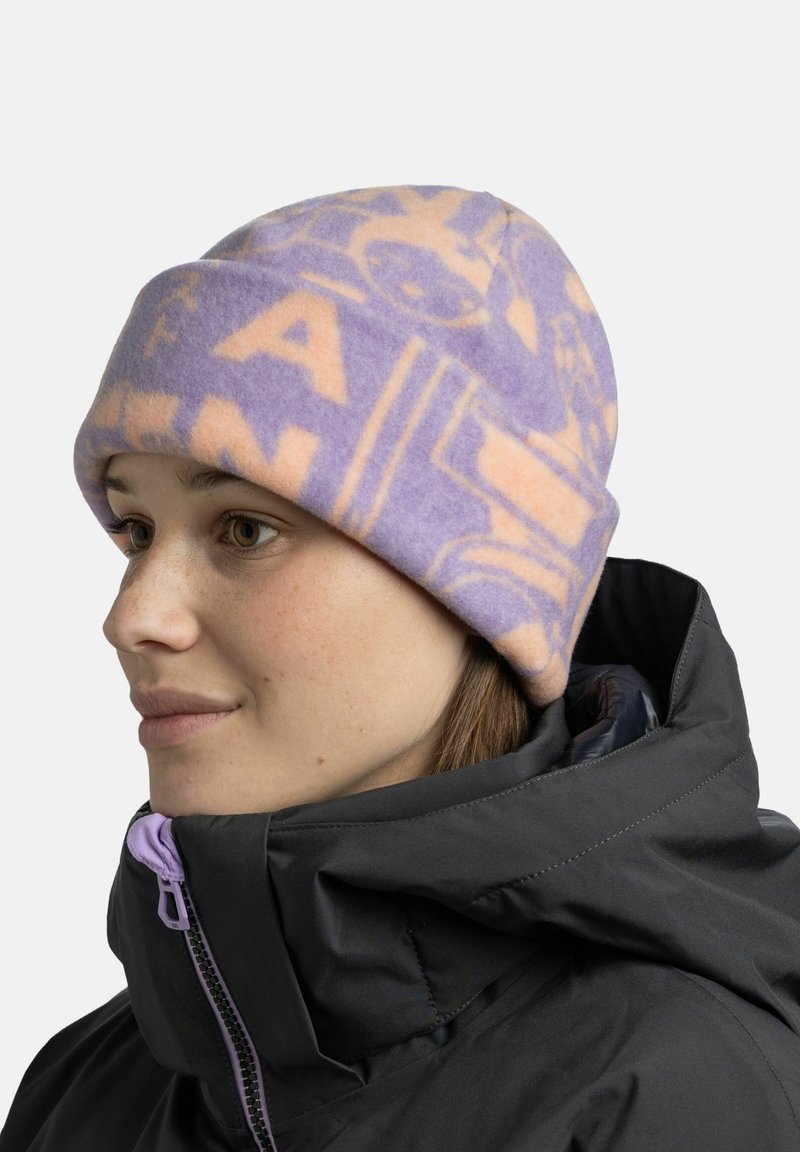Purple and peach fleece hat with graphic patterns, worn over a black jacket featuring a high collar and purple zipper detail.