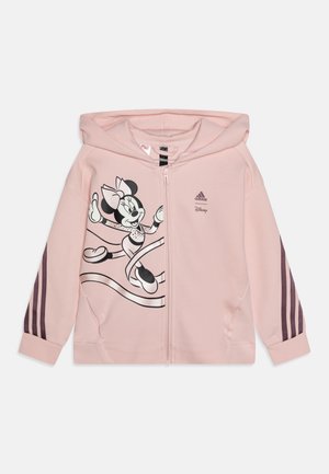 Felpa rosa con zip realizzata in morbido tessuto, caratterizzata da una grafica di Minnie Mouse in bianco e nero. Accenti di un rosa più scuro con tre strisce sulle maniche.