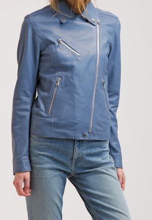 Blauwe leren motorjack met asymmetrische ritssluiting aan de voorkant en drie zilveren ritssluitingszakken, gedragen met lichtblauwe jeans.