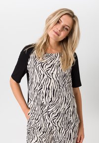 Dames top met een zwart-wit zebra print aan de voorkant, korte zwarte mouwen, ronde halslijn en een relaxte pasvorm. Zachte stof met een gladde textuur.