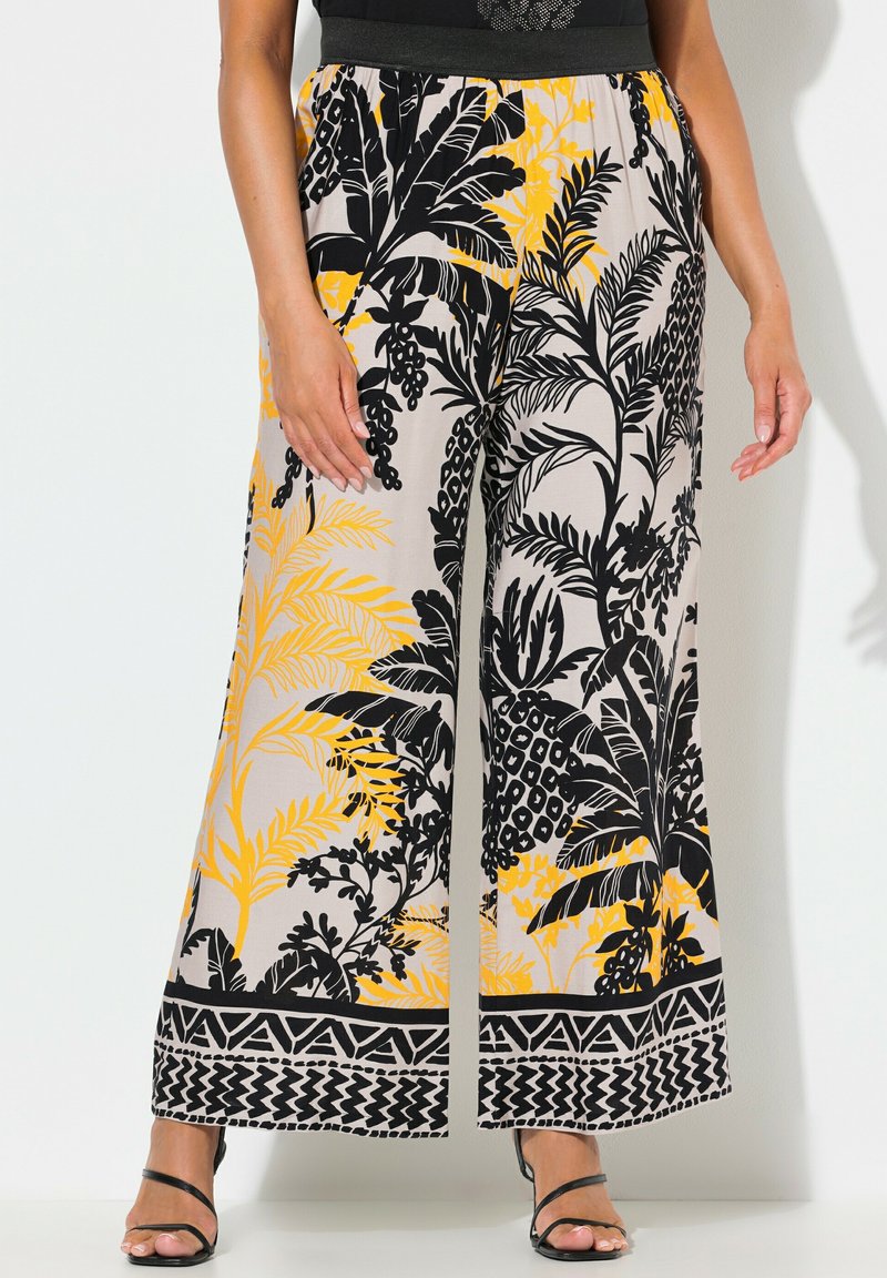 Široké kalhoty z lehké tkaniny s černým, žlutým a béžovým květinovým vzorem, s dekorativním černým lemem na spodním okraji.