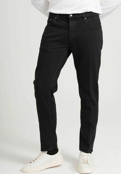 Zwarte denim broek met een slim fit, uitgerust met vijf zakken, een knoop- en ritsluiting en subtiele stikseldetails. G gedragen met witte sneakers.