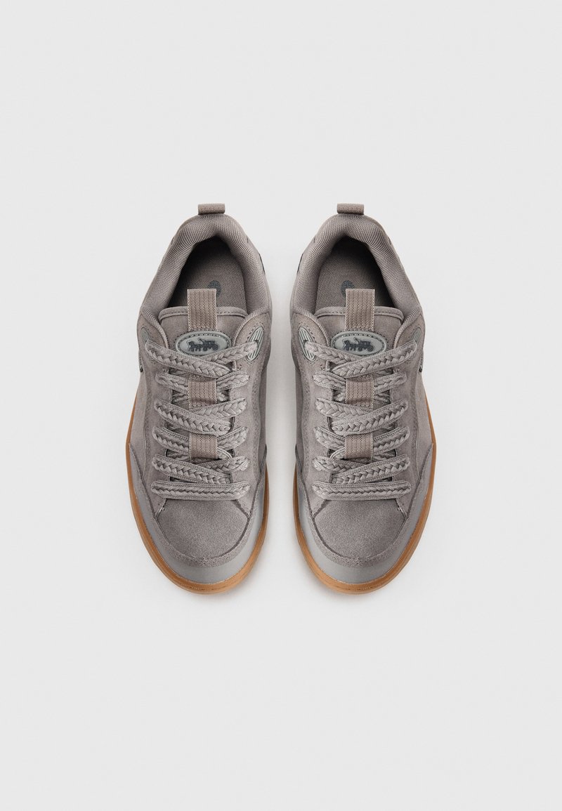 Gray suede sneakers with a textured finish, round laces, padded collar, and rubber sole. Distinctive logo on the tongue. Top view.